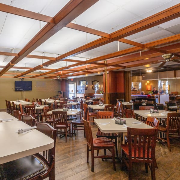 Spacious Town House Restaurant dining room with numerous tables, chairs, and a bar area with a person.