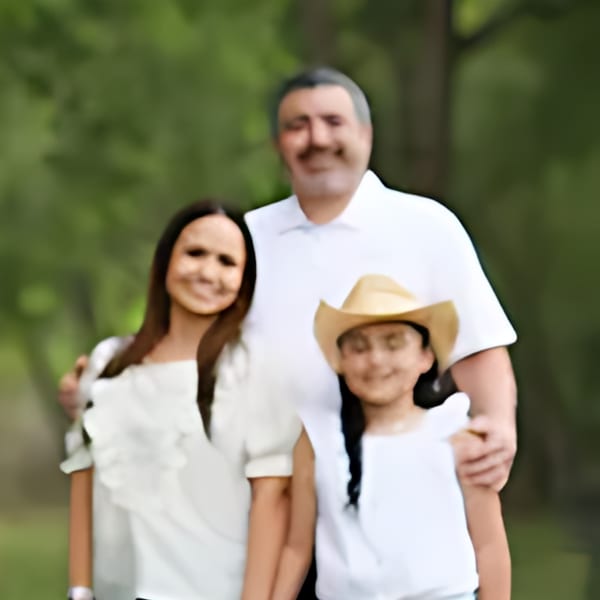 A family of three, a man, woman, and girl in a cowboy hat, smiling outdoors.