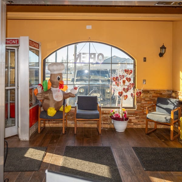 Restaurant waiting area with an inflatable turkey chef, telephone booth, and heart-decorated tree.