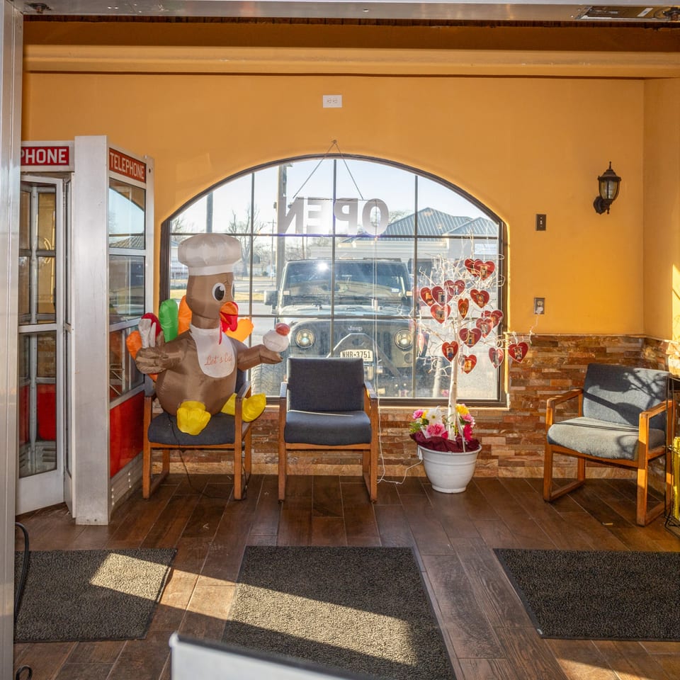 Restaurant waiting area with an inflatable turkey chef, telephone booth, and heart-decorated tree.