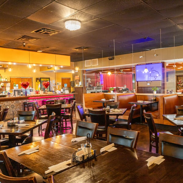 Town House Restaurant's dining room with wooden tables, booths, and a bar with pink lighting.