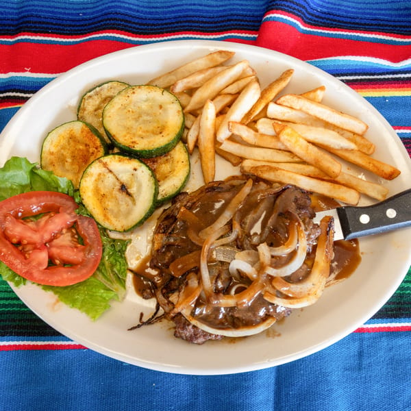 Chicken fried steak with gravy and onions, fries, grilled zucchini, and a side salad.