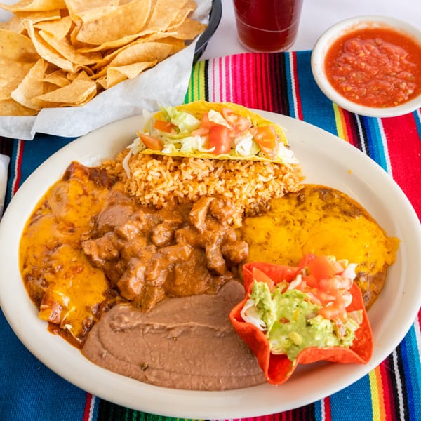A Tex-Mex combo plate with enchiladas, chili con carne, refried beans, rice, a taco, and guacamole.